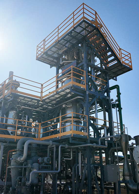Estructura industrial metálica con plataformas, escaleras y tuberías en una planta de tratamiento, bajo cielo despejado.